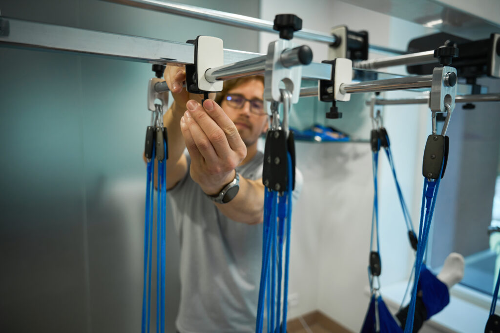 Technician assembling suspension fitness equipment system in a modern facility.