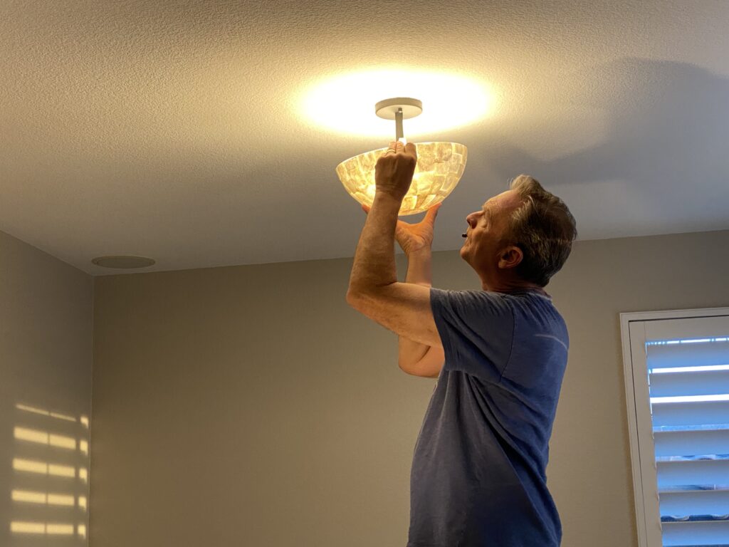 Technician performing fan & light fixture installation in a residential room