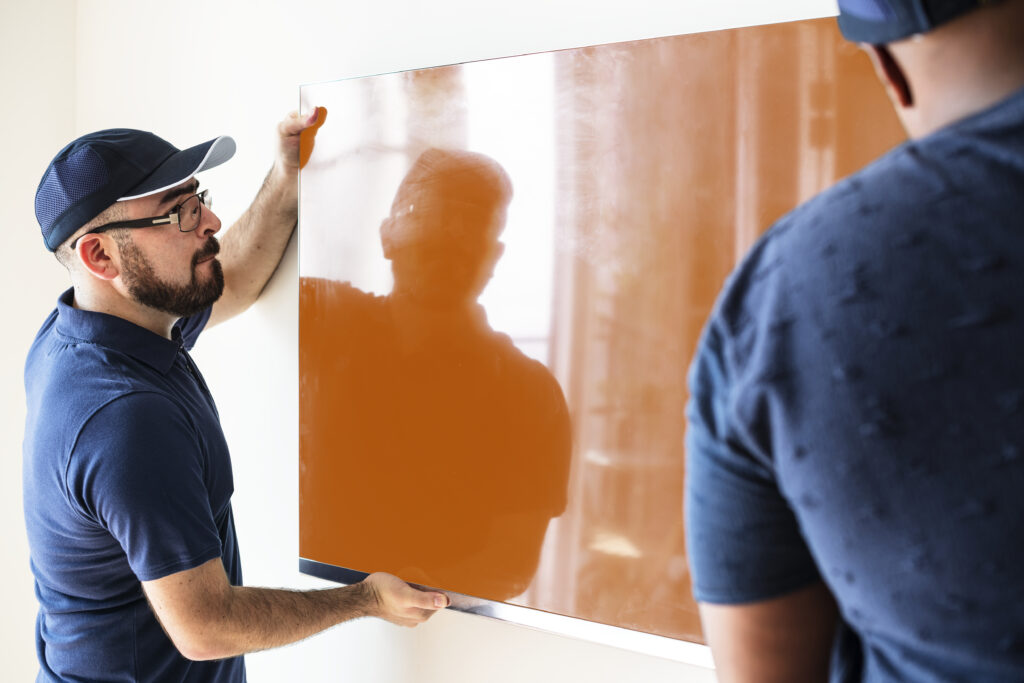Professional installing a wall mirror using a hammer for perfect wall art and mirror installation.