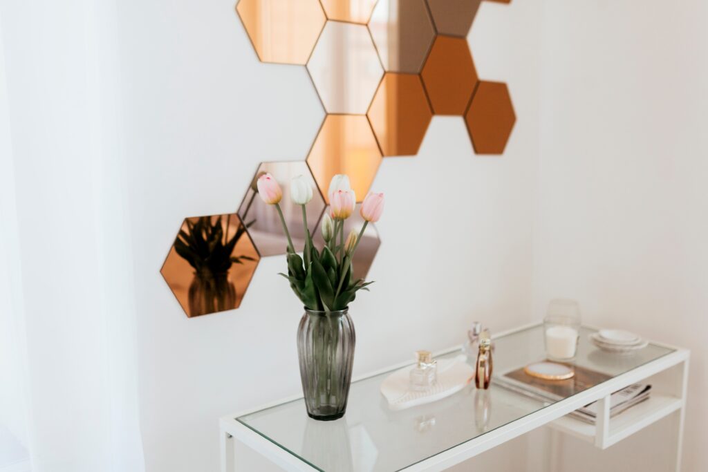 Stylish hexagonal mirror wall art with fresh flowers in a modern interior design.